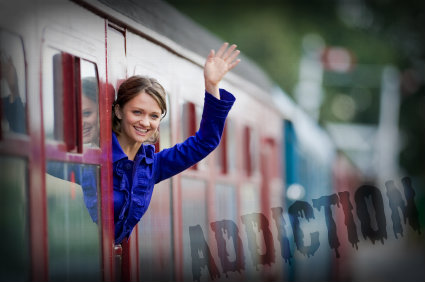 Young woman waving goodbye as she leans out of a railway carriage window